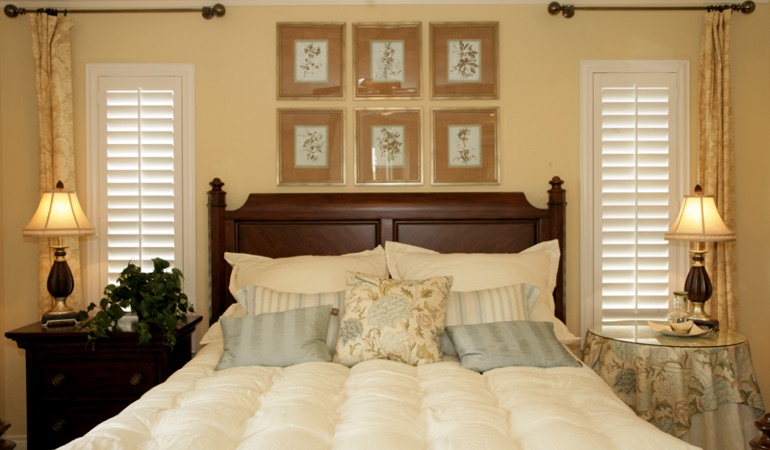 Tall plantation shutters framing bed in a bedroom in Detroit 